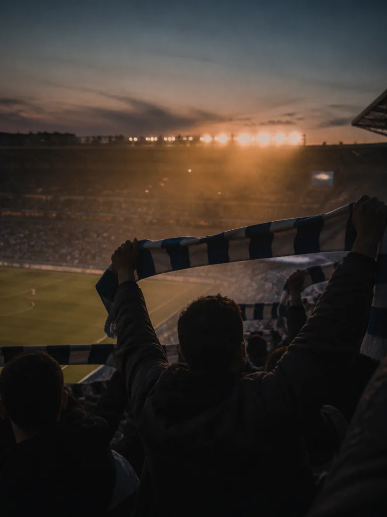 Norra Ståplats på Gamla Ullevi i kvällsljus med blåvita halsdukar